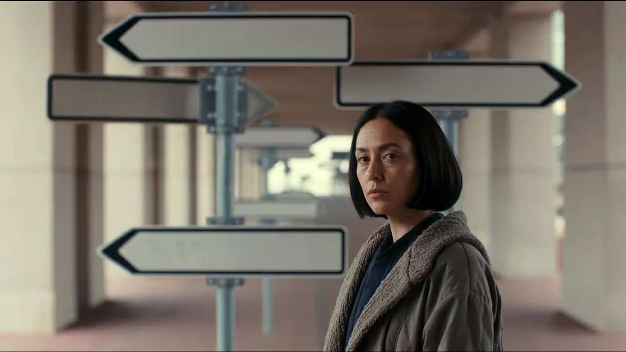 Person standing at a junction with multiple direction signs blurred, appearing unsure which way to go.